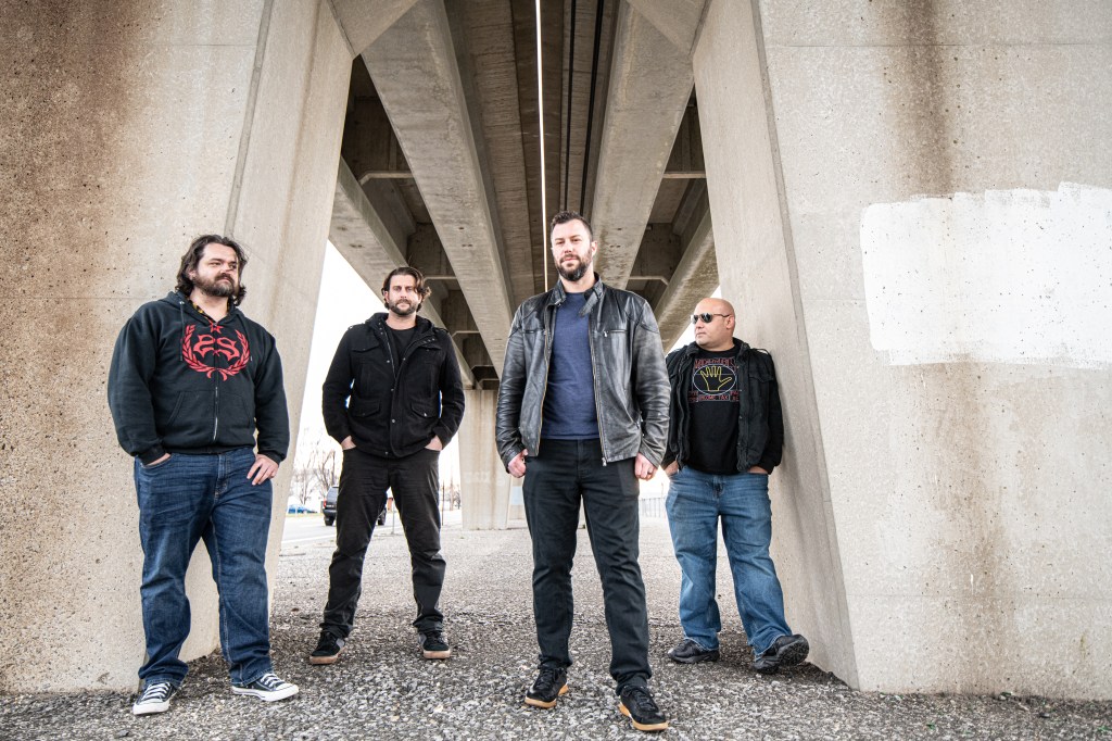 The fours members of The Fulcrum standing beneath a train trestle.